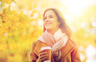 Image showing happy young woman drinking coffee in autumn park