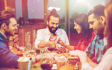 Image showing friends eating and tasting food at restaurant