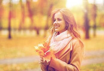 Image showing beautiful woman with maple leaves in autumn park