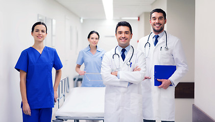 Image showing group of happy doctors with gurney at hospital