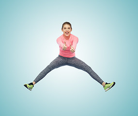 Image showing happy smiling sporty young woman jumping in air