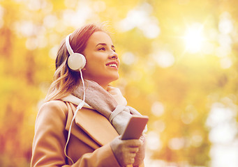 Image showing woman with smartphone and earphones in autumn park