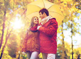 Image showing smiling couple with umbrella in autumn park