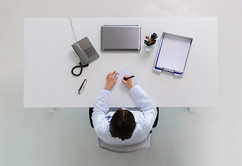 Image showing doctor writing prescription at table