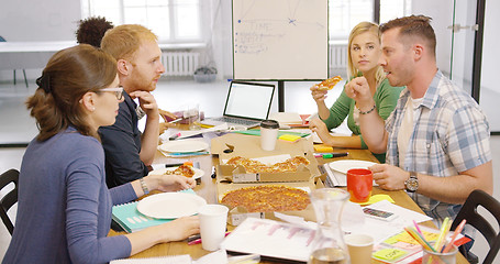 Image showing Young people enjoying pizza in office