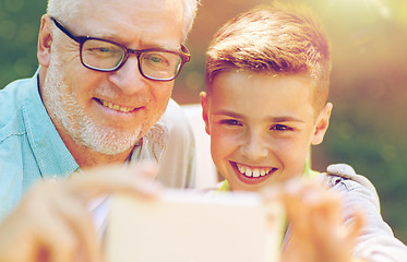 Image showing old man and boy taking selfie by smartphone