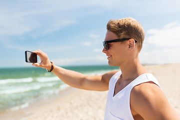 Image showing man with smartphone photographing on summer beach