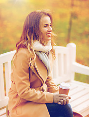 Image showing happy young woman drinking coffee in autumn park