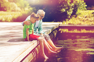 Image showing grandfather and grandson sitting on river berth