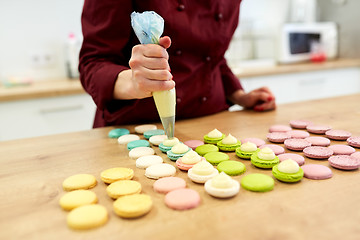 Image showing chef with injector squeezing filling to macarons