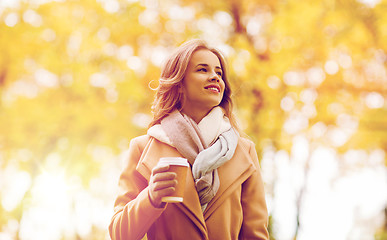 Image showing happy young woman drinking coffee in autumn park