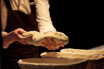 Image showing baker with dough rising in baskets at bakery