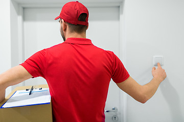 Image showing delivery man with parcel box ringing door bell