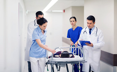 Image showing medics with woman on hospital gurney at emergency