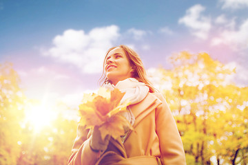 Image showing beautiful woman with maple leaves in autumn park