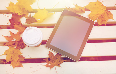 Image showing tablet pc and coffee cup on bench in autumn park