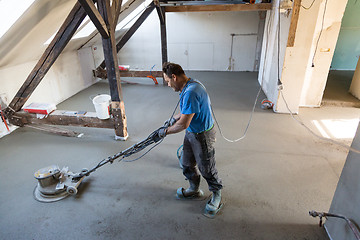 Image showing Laborer polishing sand and cement screed floor.