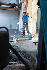 Image showing Laborer polishing sand and cement screed floor.