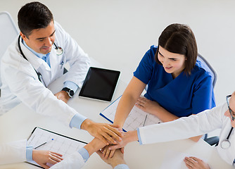 Image showing group of doctors holding hands together at table