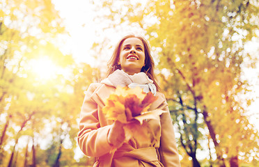 Image showing beautiful woman with maple leaves in autumn park