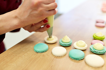 Image showing chef with injector squeezing filling to macarons