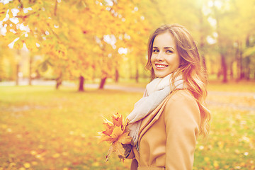 Image showing beautiful woman with maple leaves in autumn park