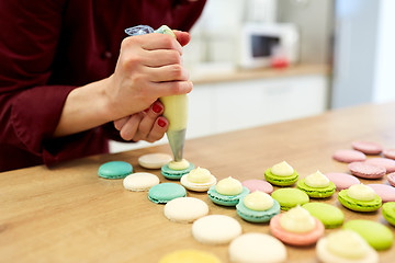 Image showing chef with injector squeezing filling to macarons