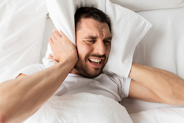 Image showing man in bed with pillow suffering from noise