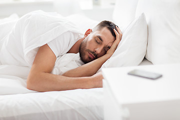 Image showing man sleeping in bed with smartphone on nightstand
