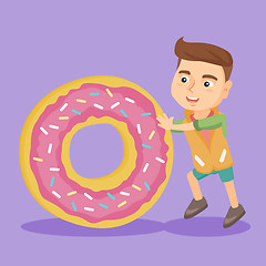 Image showing Little caucasian boy rolling a huge sweet doughnut
