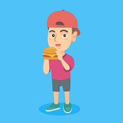 Image showing Little caucasian boy eating a hamburger.