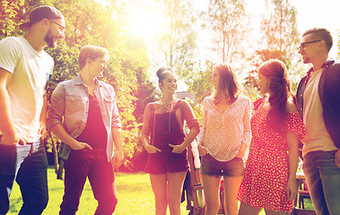 Image showing happy teenage friends talking at summer garden