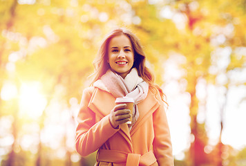 Image showing happy young woman drinking coffee in autumn park