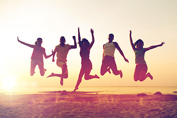 Image showing smiling friends dancing and jumping on beach