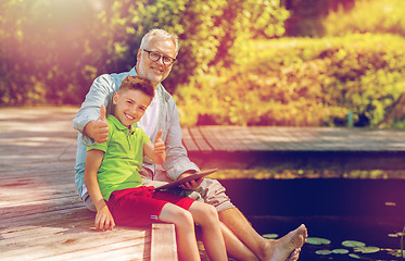 Image showing grandfather and boy with tablet pc on river berth