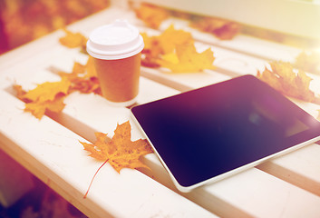 Image showing tablet pc and coffee cup on bench in autumn park