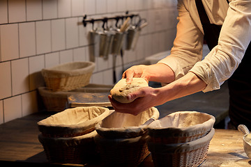 Image showing baker with dough rising in baskets at bakery