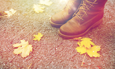 Image showing female feet in boots and autumn leaves