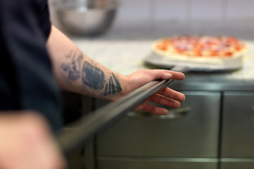 Image showing cook or baker hand with pizza on peel at pizzeria