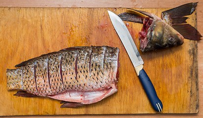 Image showing The brushed and cut fish lies on the cutting board, next to it lies a knife