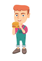 Image showing Little caucasian boy eating a hamburger.