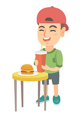 Image showing Little boy drinking soda and eating cheeseburger.