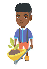 Image showing Boy pushing wheelbarrow with soil and plant.