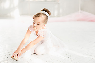 Image showing Little ballerina girl in a tutu. Adorable child dancing classical ballet in a white studio.