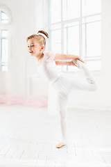 Image showing Little ballerina girl in a tutu. Adorable child dancing classical ballet in a white studio.