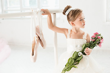 Image showing Little ballerina girl in a tutu. Adorable child dancing classical ballet in a white studio.