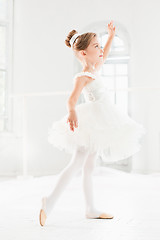 Image showing Little ballerina girl in a tutu. Adorable child dancing classical ballet in a white studio.