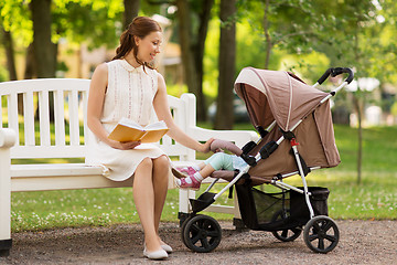 Image showing mother with child in stroller reading book at park