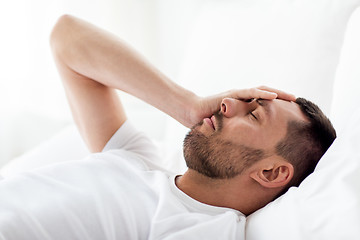 Image showing man in bed at home suffering from headache