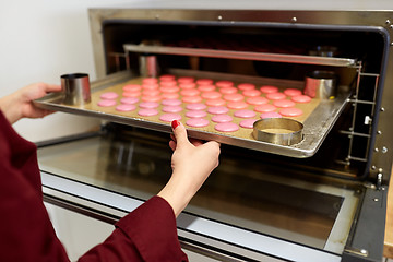 Image showing chef with macarons on oven tray at confectionery